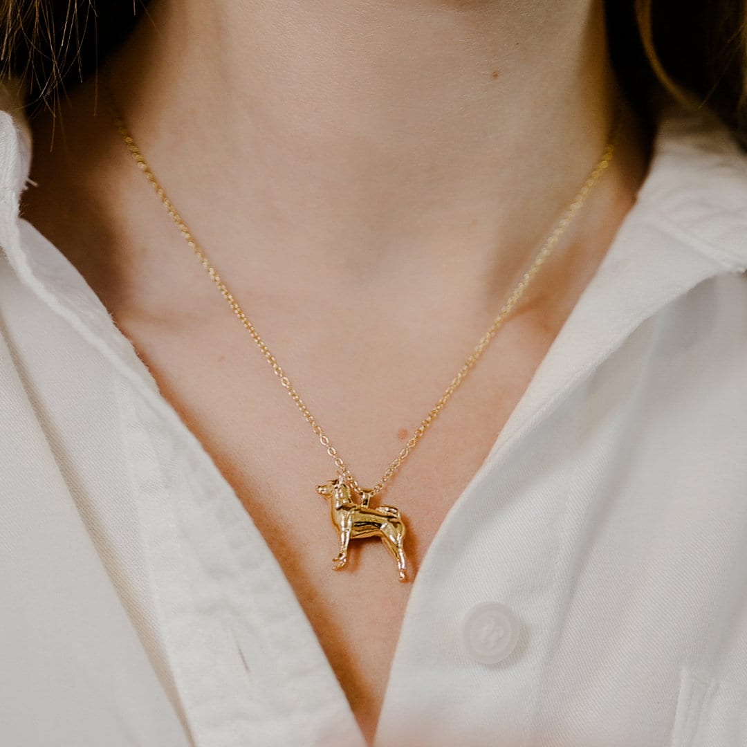 May include: A gold chain necklace with a gold dog pendant.