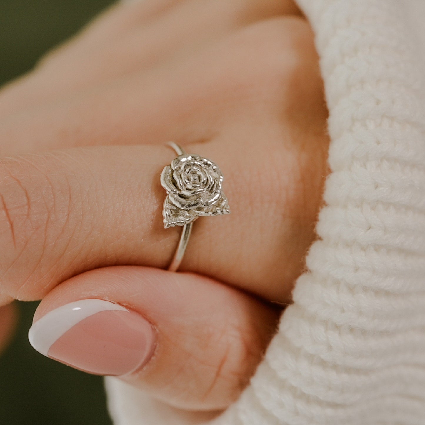 May include: A silver ring with a rose design