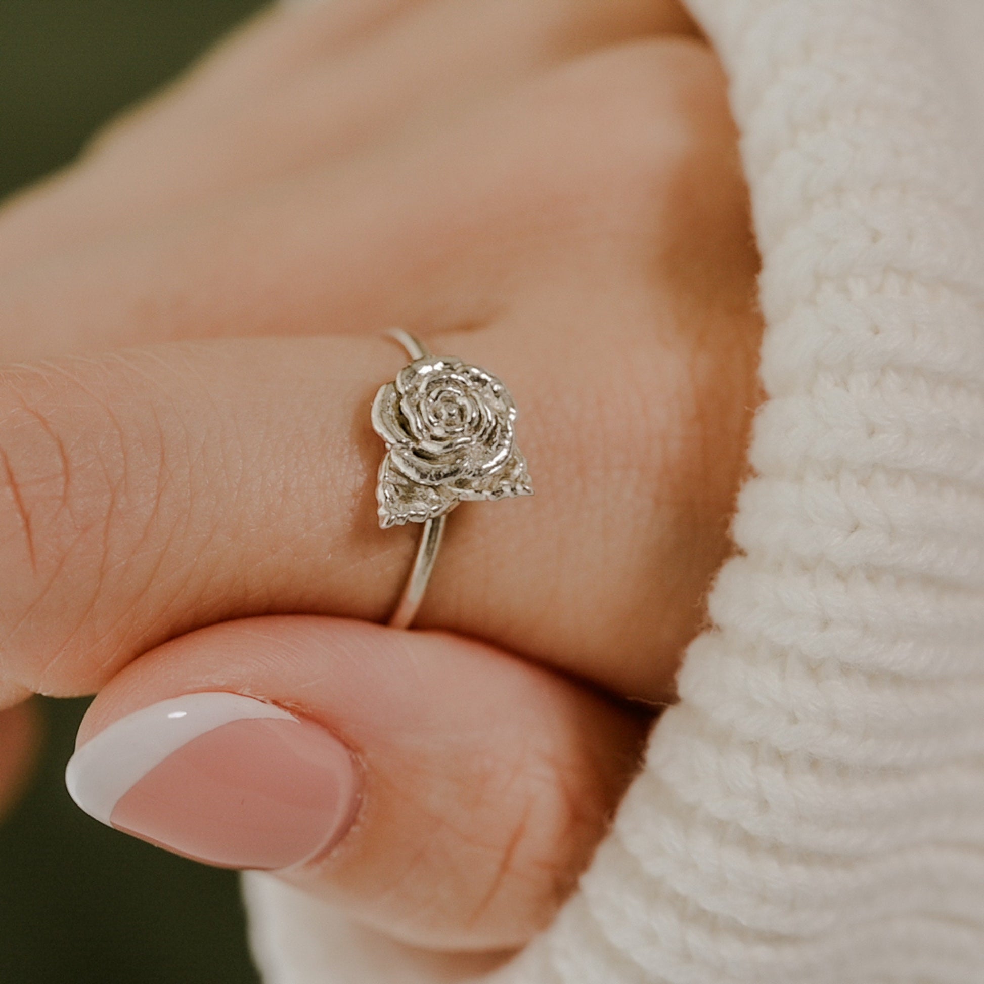 May include: A silver ring with a rose design